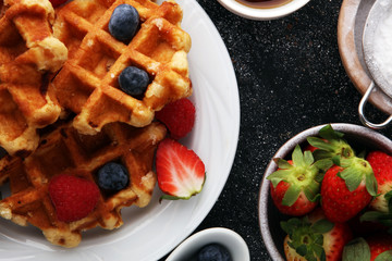 Traditional belgian waffles with fresh fruit and powder sugar on wooden board