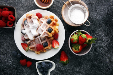 Traditional belgian waffles with fresh fruit and powder sugar on wooden board