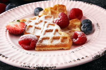 Traditional belgian waffles with fresh fruit and powder sugar on wooden board