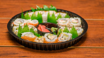 Large set of japanese sushi rolls on a black plastic plate