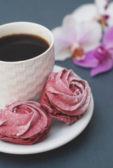Sweet Pink Meringues and Cup of Coffee on Blue Gray background with Orchid Flowers. Spring Background with copy space. Breakfast.
