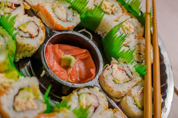 Close up of selective focus of large set of delicious japanese sushi rolls on a black plastic plate