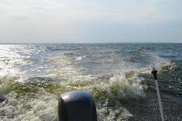 Storm, wind, motor boat floating on the waves on the lake - view from the stern to the outboard...
