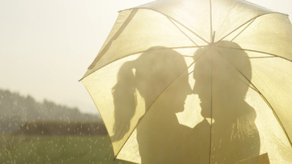 CLOSE UP: Man and woman in love hide behind umbrella as they are about to kiss.