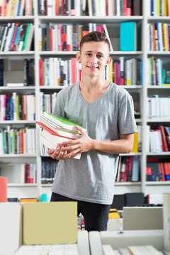 Portrait of smiling teenager boy with book pile