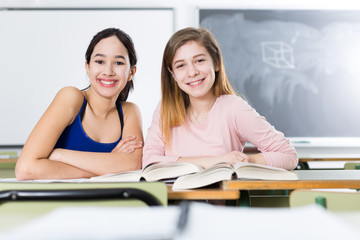 Young girls are sitting at the desk in the classroom