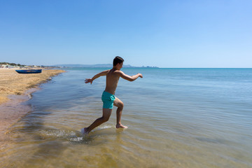 a young man runs into the sea