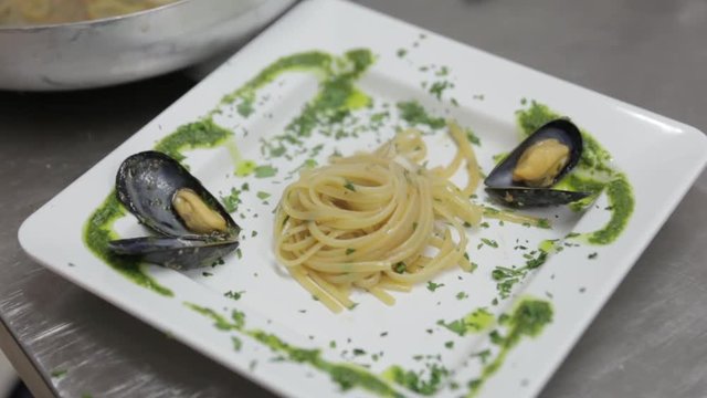 Close up, chef places pasta on plate