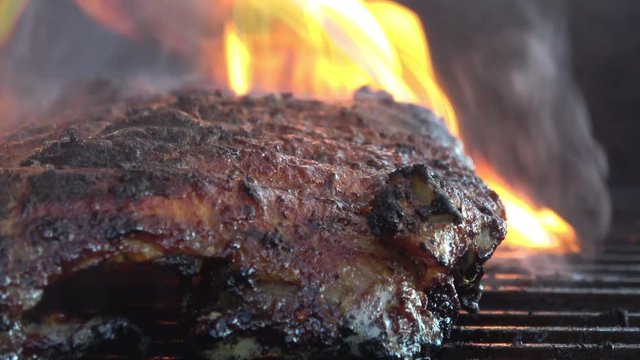 Grilling a rack of Baby Back Ribs on the Barbecue with smoke and flames.