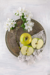 freh ripe green apple decorated with beautiful apple blossom on white wooden table, rustic food photography with vintage look