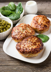 Homemade cutlets   with green peas on a plate in a rustic style.