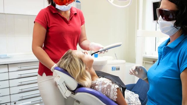 4k video of dentist assistant holding curing UV lamp for hardening photopolymer on patient's teeth