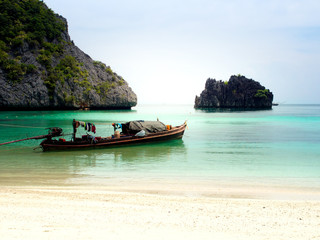 Fototapeta na wymiar White sand beach and fisher man's boat in the blue sea.