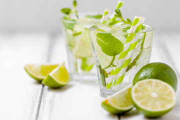 Summer refreshing cocktail mojito with lime and mint on white wooden vintage background.