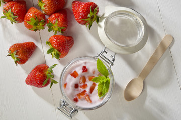 Yogurt with fresh strawberries and mint leaf in a glass jar