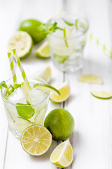 Summer refreshing cocktail mojito with lime and mint on white wooden vintage background.