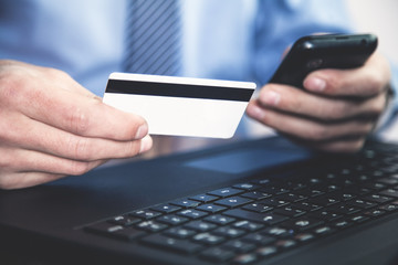 Man holding credit card and using phone.