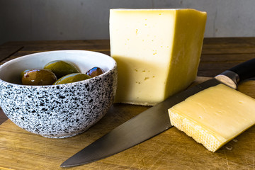 Tipico spuntino mediterraneo, olive greche e formaggio italiano di montagna, su una tavola di legno