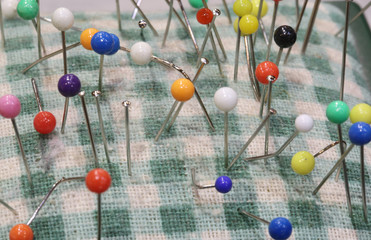 colored pins for sewing stuck on a pincushion