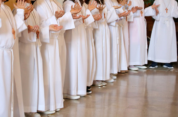 many little children during the first communion with white cloth