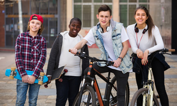 Teens with bikes and skates outdoors.