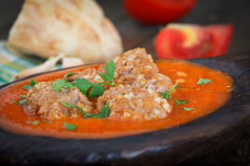 Meatballs with tomato sauce and spices, vintage wooden plate, closeup