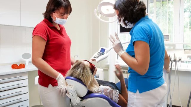 4k footage of young woman sitting in dental chair and talking with dentist before teeth whitening