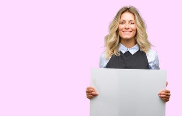 Young shop owner wearing black apron holding blank advertising banner, good poster for ad, offer or announcement, big paper billboard