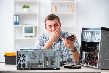 Young technician repairing computer in workshop