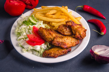 Chicken wings and fries with salad