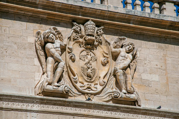 Detail of stone ornament of building in front of the Palace of the Popes of Avignon, under a sunny blue sky. Located in the Vaucluse department, Provence-Alpes-Côte d'Azur region, southeastern France