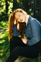 Obraz premium Amazing redhead young model in denim shirt posing in rays of sun at the forest