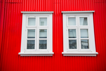 Windows in house in reykjavik, iceland. Building facade with red wall and white window frames. Architecture structure and design