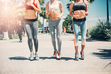 Do sport and be fit. Slender bodies of young women jogging on alley in the park