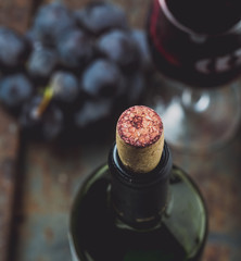 Top view of red wine bottle. Macro selective focus on wine cork. Wine bottle, wine glass and grape on vintage background. Copi space, wine concept