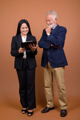 Mature multi-ethnic business couple against brown background