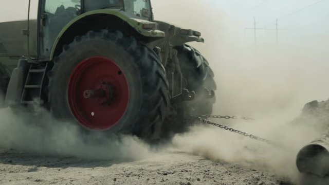 A tractor with an agricultural machine processes the soil, a lot of dust rises. The problem of soil erosion