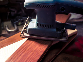 close up hand with grinder machine in the workshop working with wood plank
