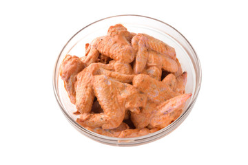 Marinated chicken wings in a glass bowl. Glass dish with pickled wings on a white background.