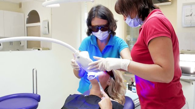 4k video of female dentist turning on special UV lamp for teeth whitening procedure