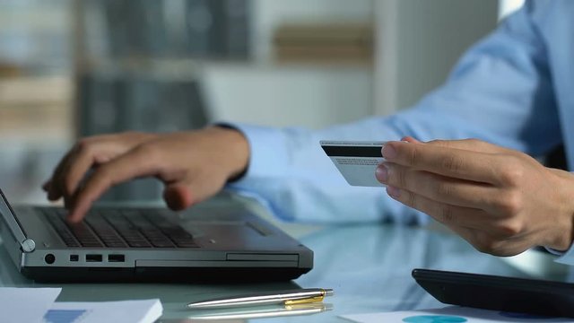 Man making online payment on computer, using card for internet banking services