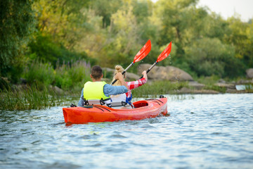 Young Happy Couple Paddling Kayak on Beautiful River or Lake