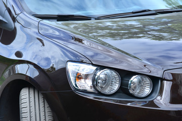 The headlight on a brown car, close-up, polished glass for road lighting while driving.
