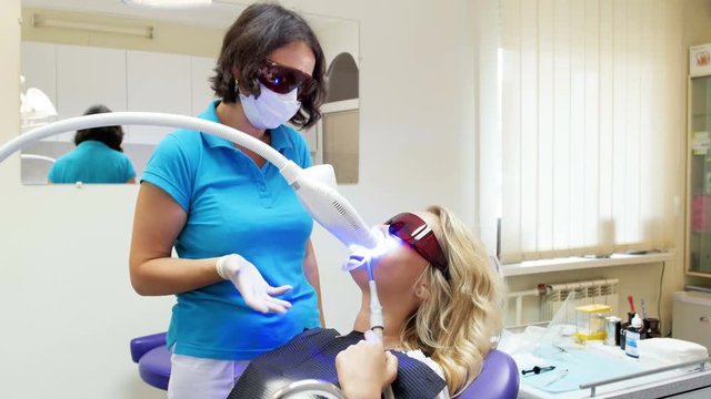 4k video of beautiful blonde woman lying in dentist chair during teeth whitening