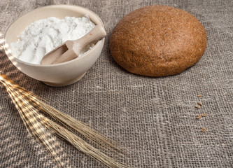  Bunch of wheat ears, a bowl of flour and round bread.