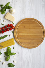 Round board with ingredients for cooking italian pasta on a white wooden background. Flat lay. Top view. Copy space