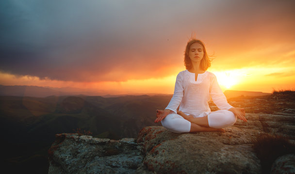 woman practices yoga and meditates   on mountains .