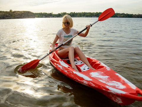 Young Happy Woman Paddling Kayak on Beautiful River or Lake at Sunset