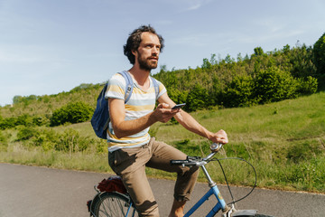 Obraz premium young caucasian man biking through a field of rapeseeds