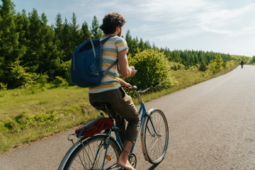 Obraz premium young caucasian man biking through a field of rapeseeds